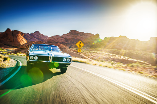 couple driving together in cool vintage car through desert at high speed.