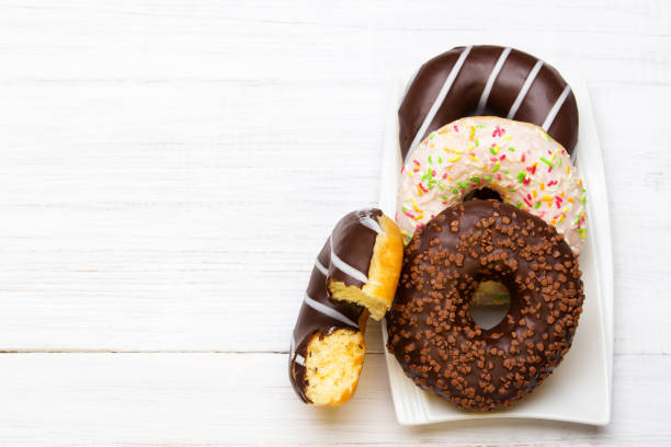 istock Tasty donuts with icing and chocolate on white wooden background 647369068