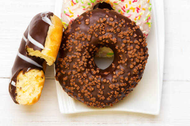 istock Tasty donuts with icing and chocolate on white wooden background 647369264
