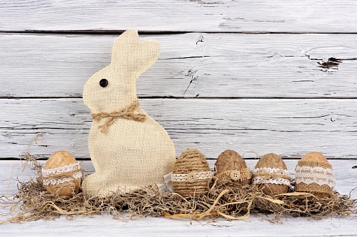Handmade rustic style Easter eggs and bunny in moss against an aged white wood background
