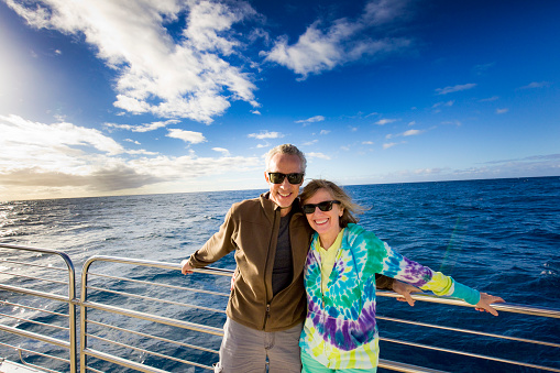 Mature adult tourist couple enjoying cruise ship boat tour. Photographed on location in Hawaii in horizontal format with copy space available.