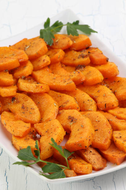 istock Butternut slices baked in spicy dressing on white plate 647416580