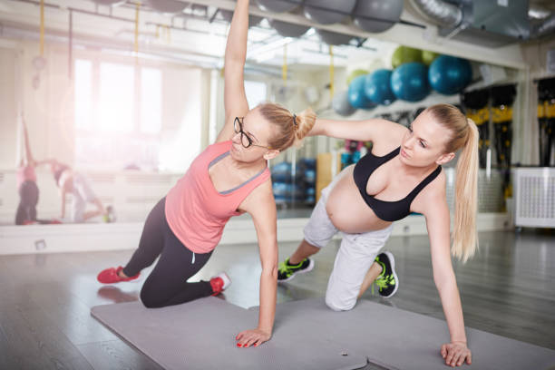 istock Pregnant woman exercising with personal trainer 647420336
