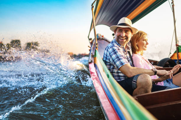 uomo di mezza età e la sua compagna bella signora bionda in un giro in barca a bangkok - bangkok thailand asia water taxi foto e immagini stock