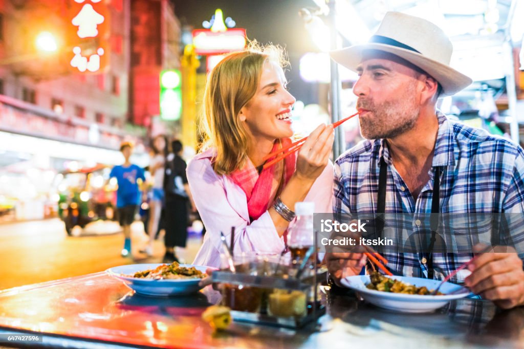 Middle-aged man and his companion handsome blond lady in Bangkok Chinatown Middle-aged man and his companion handsome blond lady on a tuk-tuk ride in Bangkok Food Stock Photo