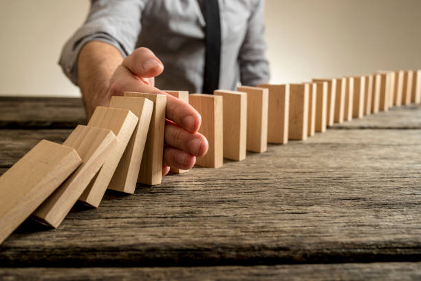 istock Man stopping domino effect on wooden table 647430576