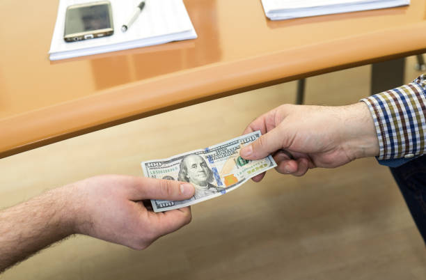 istock Man offering of hundred dollar bill. Hands close up. 647433660