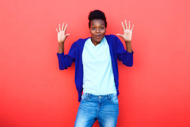 istock Surprised young woman standing with her hands raised 647437276