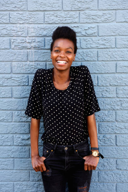istock Smiling african woman standing against gray brick wall 647437582