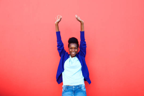 Excited young african woman standing with her arms raised