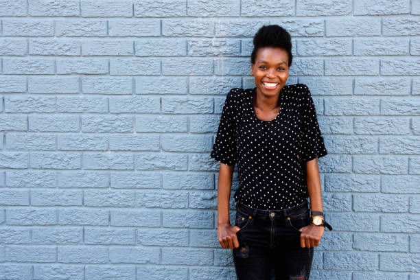 istock Happy african female standing against gray brick wall 647437602