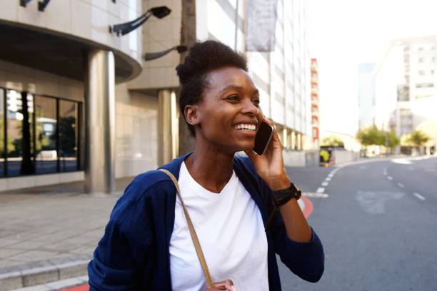 istock Smiling black woman walking outdoors and talking on cellphone 647437674