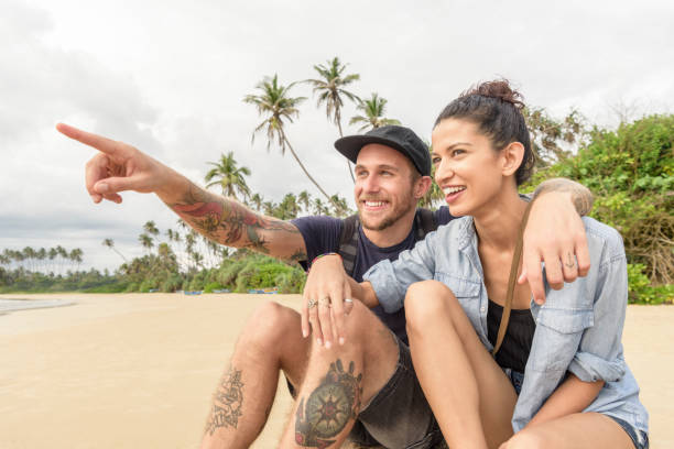 istock Man with tattoos and arm around woman pointing to distance 647438708