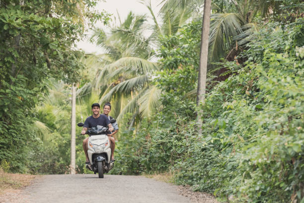 istock Couple riding moped on rural road though trees, Sri Lanka 647438988