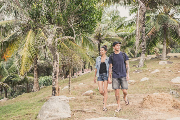 istock Mid adult couple walking through palm trees on vacation 647441462