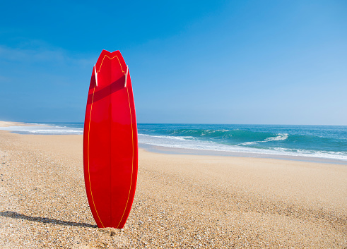 Beach landscape with a red surfboard on the sand
