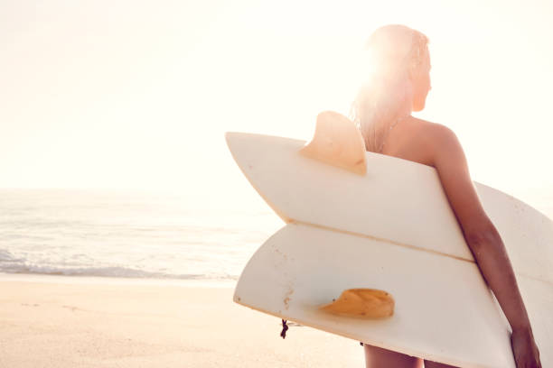 Surf lifestyle Beautiful young woman holding her surfboard after a day of surf surfboard fin stock pictures, royalty-free photos & images