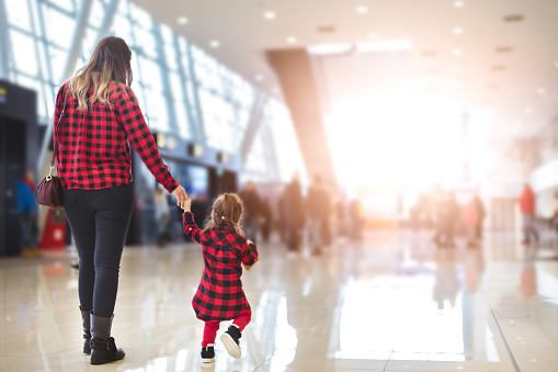 mom and her little girl walking in an airport hall