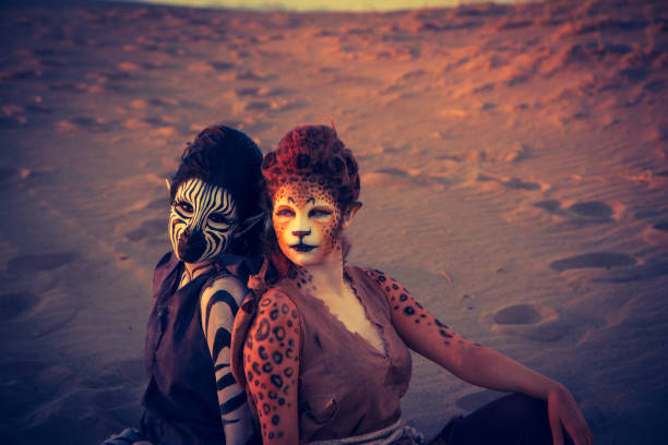 Male and female actors wearing Anthropomorphic animal makeup in the dessert. There is a lion, a zebra and a cheetah.