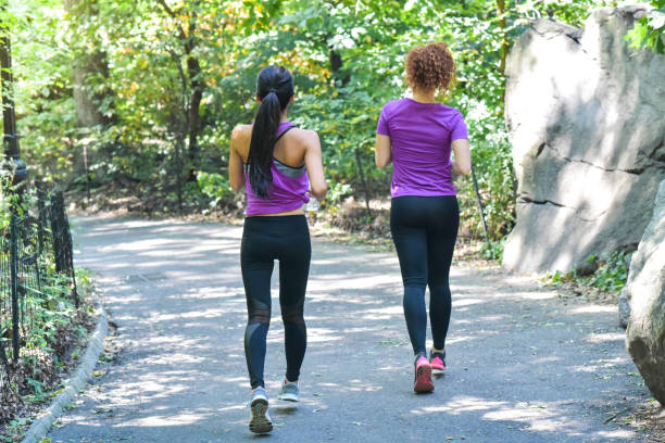 Friends taking a Jog Two young women take a jog in a park during a beautiful spring day racewalking stock pictures, royalty-free photos & images