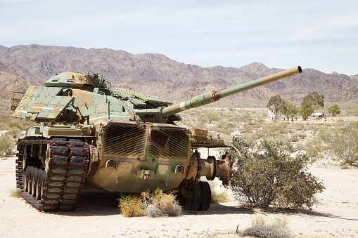 An army tank, somewhat worse for the wear and broken down, sits in the desert of Southern California, awaiting repair, recovery, or rust.