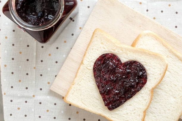 istock Toast with jam in shape of hearts on tablecloth background.Top view 647514188
