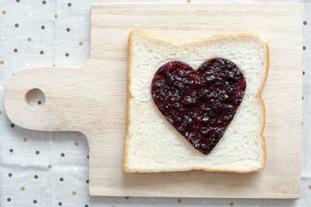 istock Toast with jam in shape of hearts on tablecloth background.Top view 647514264