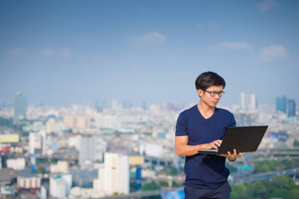 istock Young business man using laptop and digital tablet cityscape background 647520252