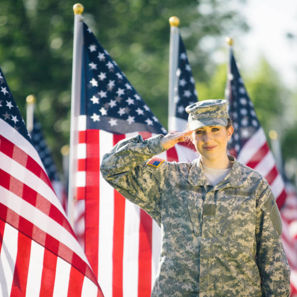 soldado americano feminino, saudando em um campo de bandeiras americanas - armed forces latin american and hispanic ethnicity saluting marines - fotografias e filmes do acervo