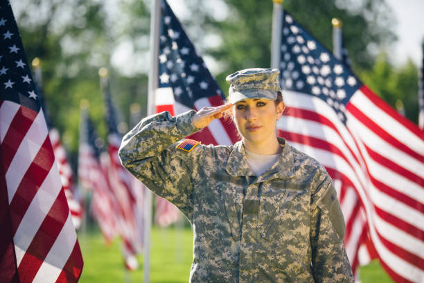 soldado americano feminino, saudando em um campo de bandeiras americanas - armed forces latin american and hispanic ethnicity saluting marines - fotografias e filmes do acervo