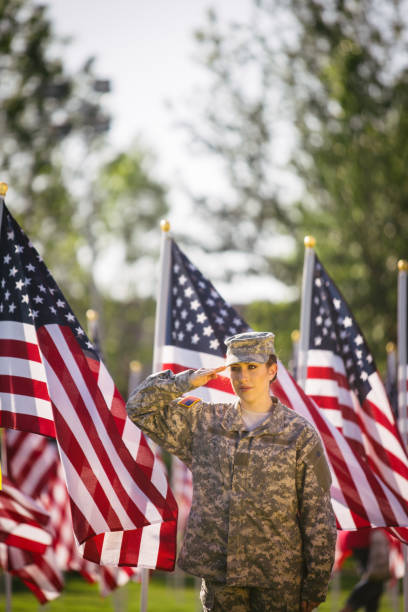 soldado americano feminino, saudando em um campo de bandeiras americanas - armed forces latin american and hispanic ethnicity saluting marines - fotografias e filmes do acervo