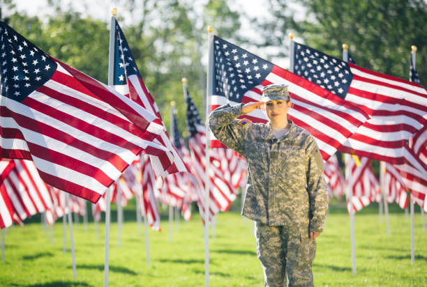 soldado americano feminino, saudando em um campo de bandeiras americanas - armed forces latin american and hispanic ethnicity saluting marines - fotografias e filmes do acervo