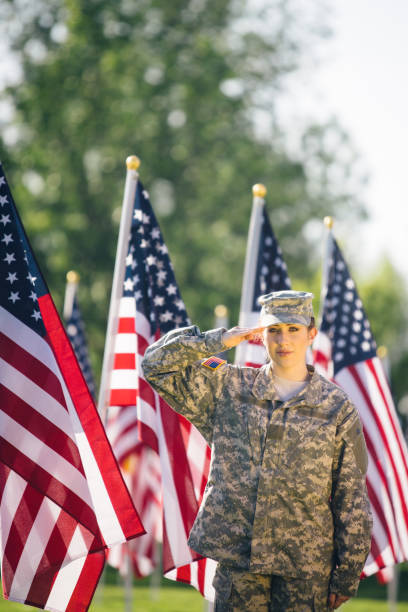 soldado americano feminino, saudando em um campo de bandeiras americanas - armed forces latin american and hispanic ethnicity saluting marines - fotografias e filmes do acervo