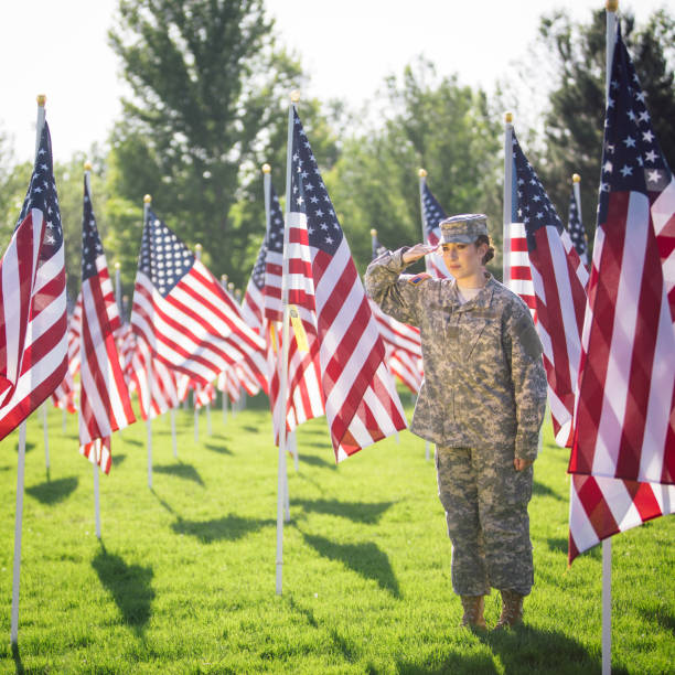 soldado americano feminino, saudando em um campo de bandeiras americanas - armed forces latin american and hispanic ethnicity saluting marines - fotografias e filmes do acervo