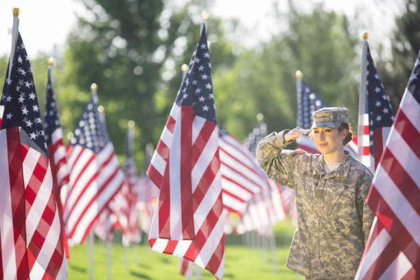 soldado americano feminino, saudando em um campo de bandeiras americanas - armed forces latin american and hispanic ethnicity saluting marines - fotografias e filmes do acervo