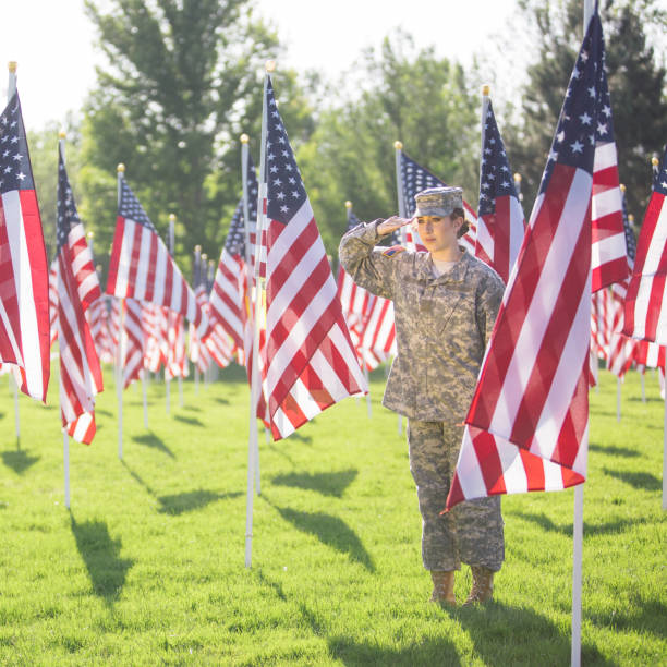 soldado americano feminino, saudando em um campo de bandeiras americanas - armed forces latin american and hispanic ethnicity saluting marines - fotografias e filmes do acervo