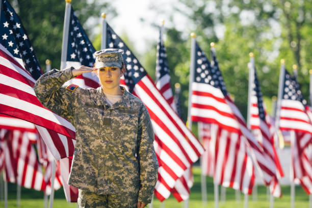 soldado americano feminino, saudando em um campo de bandeiras americanas - armed forces latin american and hispanic ethnicity saluting marines - fotografias e filmes do acervo