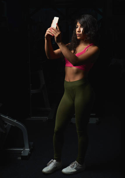 istock Young woman with smartphone in gym 647529220