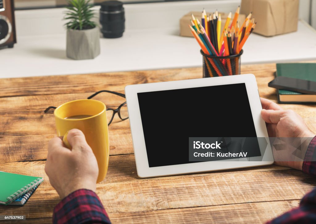 Man holding tablet with copy space Man holding tablet with copy space while sitting at the wooden table in her home office Blank Stock Photo