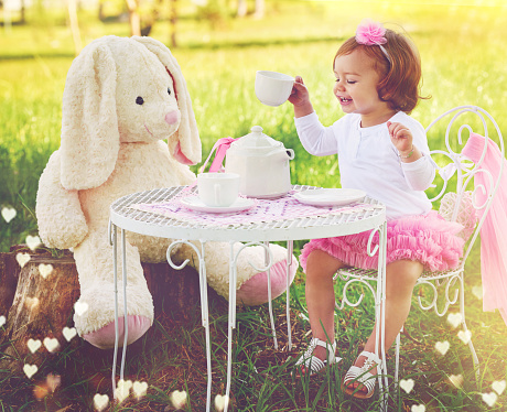 Shot of a cute little girl having a tea party with her stuffed animal on the lawn outside