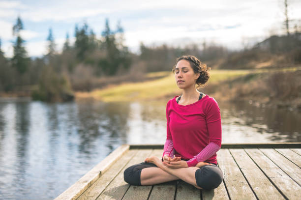 giovane mamma che fa yoga fuori in riva al lago - posizione corretta foto e immagini stock