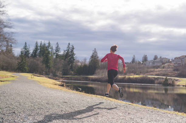 istock Young Latino woman jogging by lake 647549346