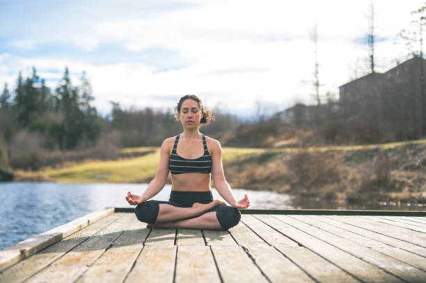 istock Young mom doing yoga outside by lake 647549358