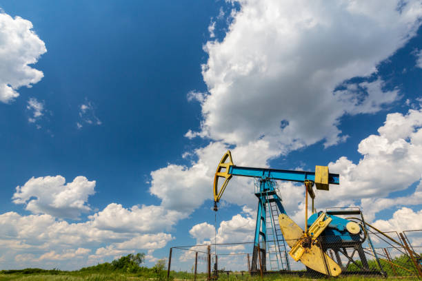 istock Oil field with pump jack, profiled on blue sky with white clouds, on a sunny day 647552096