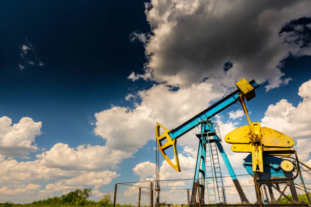 istock Oil field with pump jack, profiled on blue sky with white clouds, on a sunny day 647552434