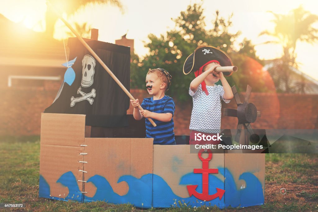 These little pirates just want to have fun Shot of a cute little boy and his brother playing pirates outside on a boat made of cardboard boxes Child Stock Photo