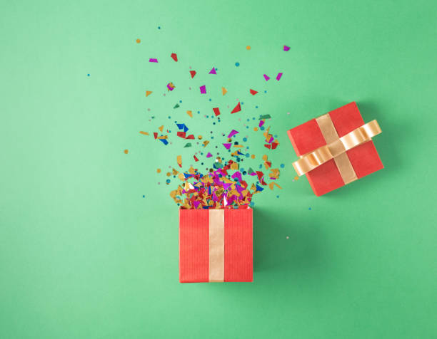 istock Open red gift box with various party confetti on a green background 647555560