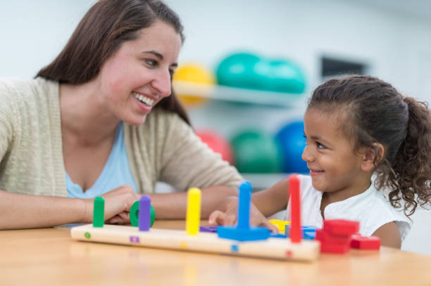 istock Occupational therapist working with young African American girl at table 647559540