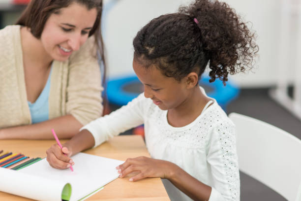 istock Occupational therapist working with young African American girl at table 647559548