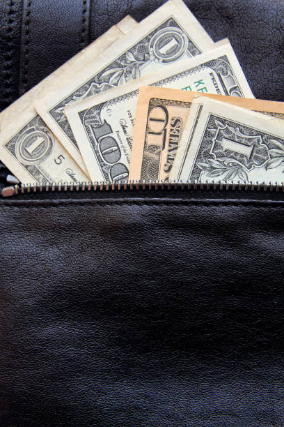istock dollar bills peeking out of black leather bag. copy space. 647570266